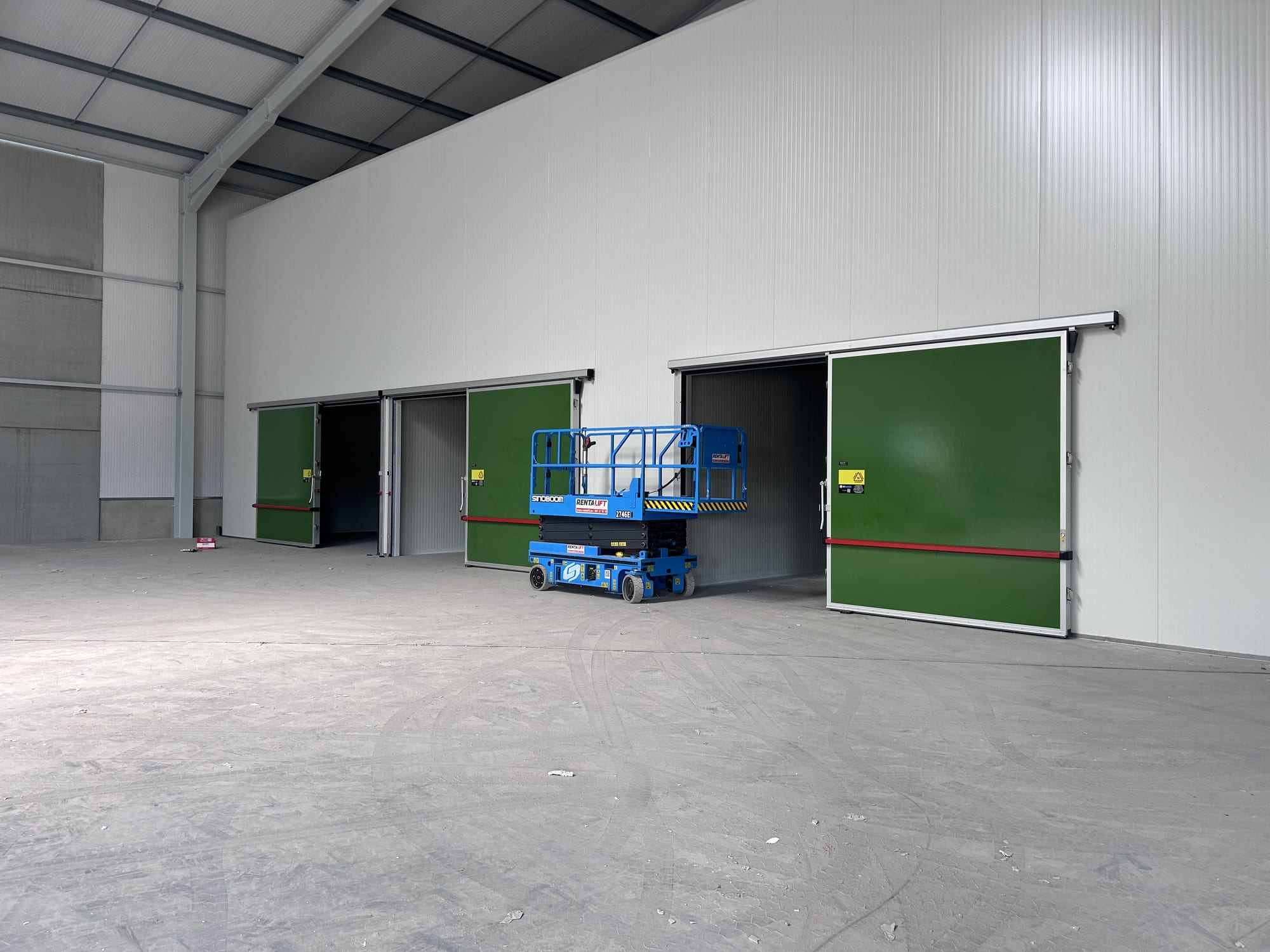 Insulated cold-store hall with green sectional doors and access platform