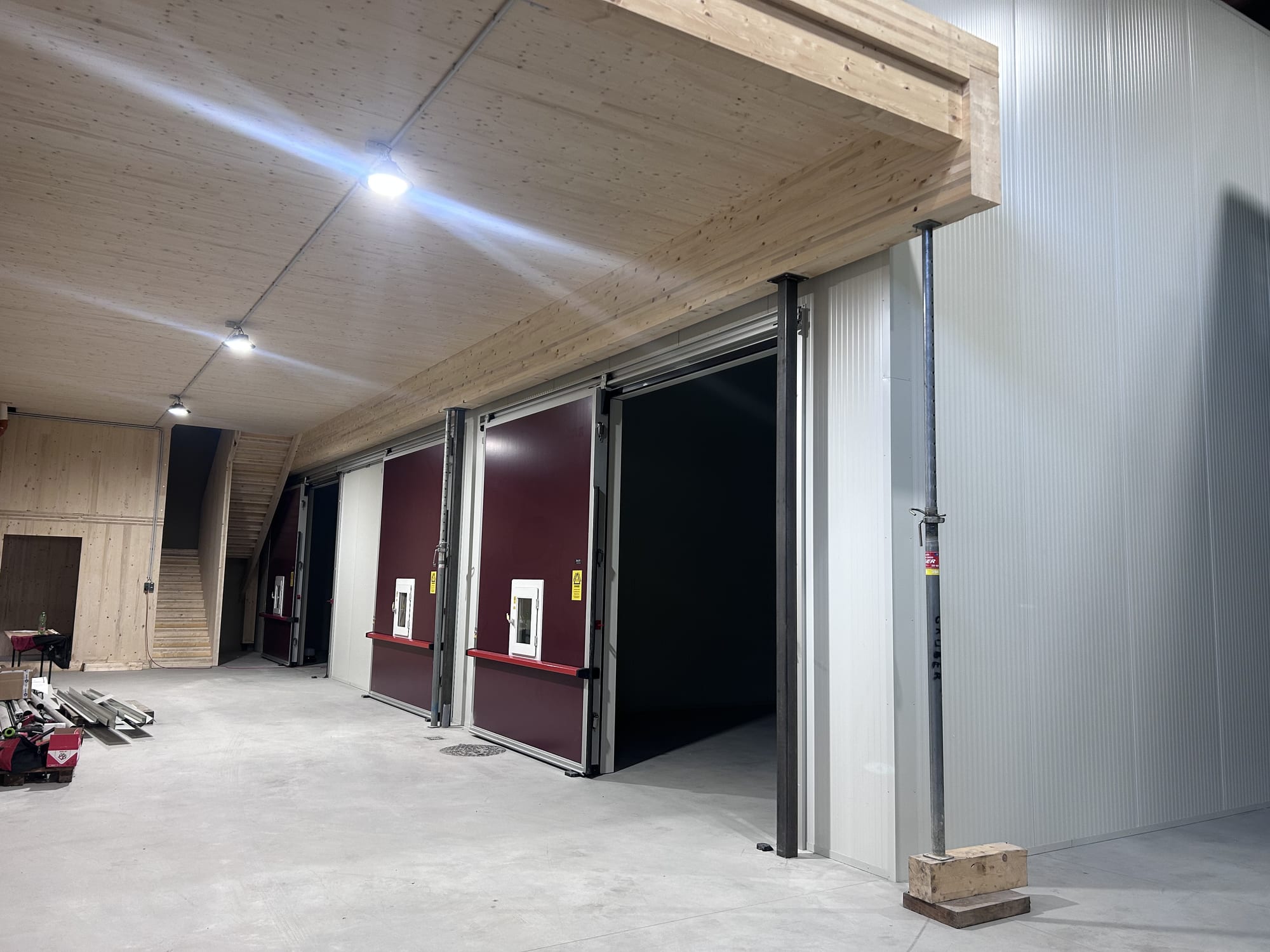 Finished hall at night with CLT timber ceiling and insulated doors